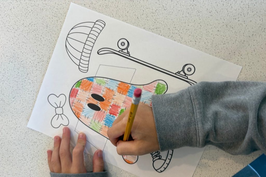 Child coloring a printable checkerboard ghost craft with a grid pattern.