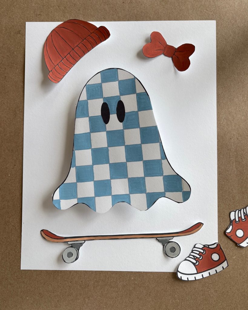 Blue checkered 3D paper ghost craft with a curved pop-out shape, surrounded by printable skateboard, sneakers, beanie, and bow accessories.